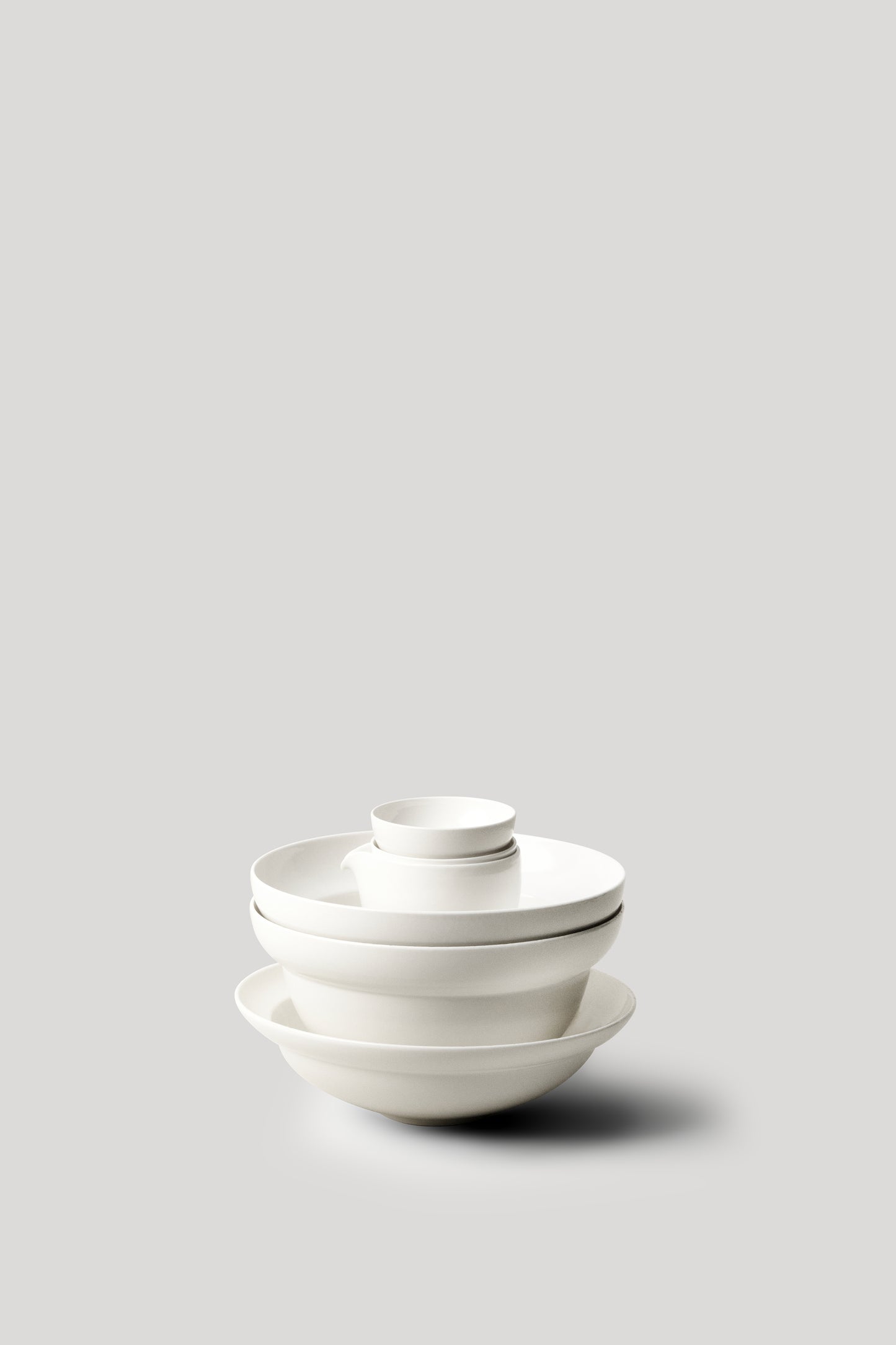 Stack of white ceramic bowls on a light gray background