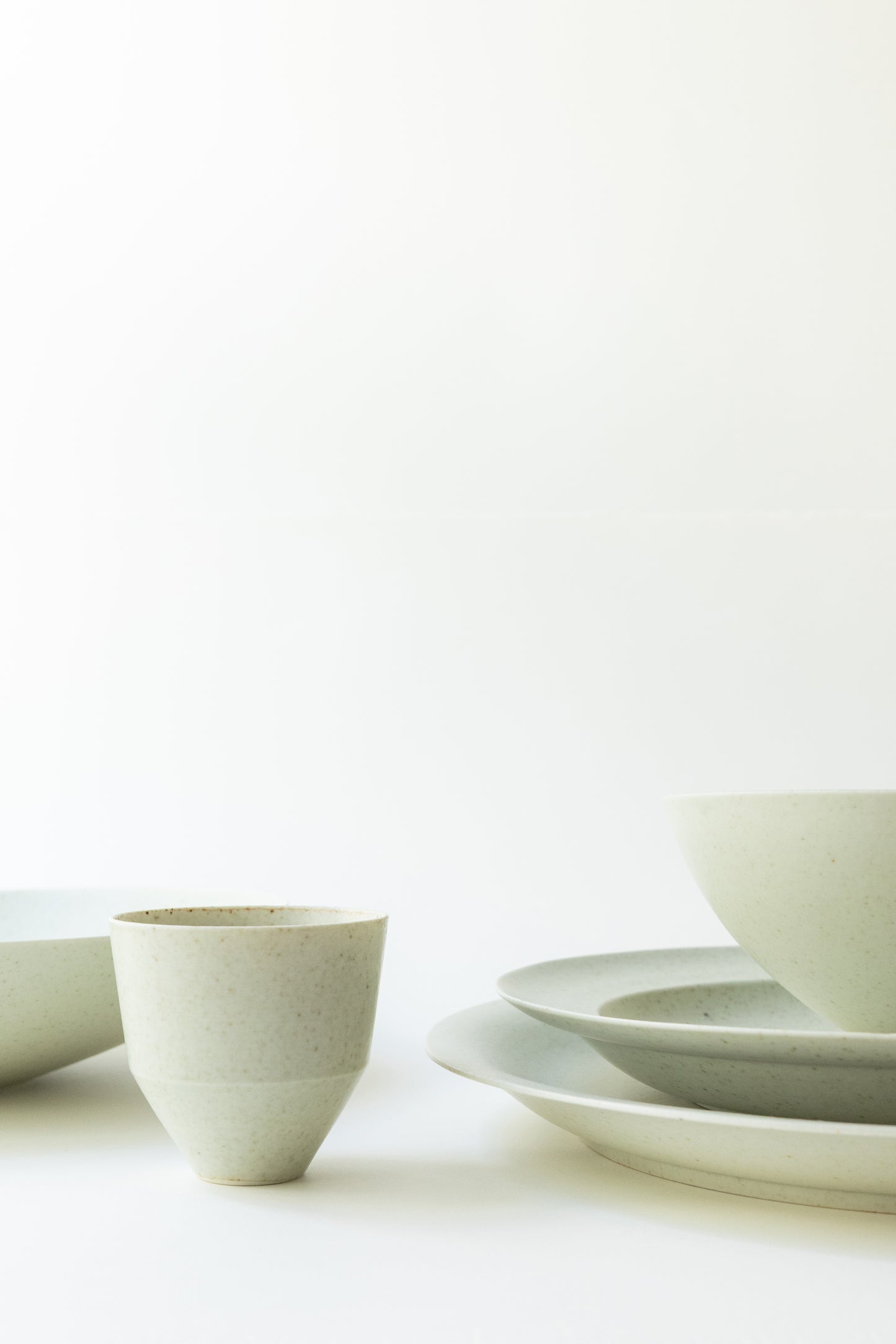 Set of white ceramic bowls and plates on a light background