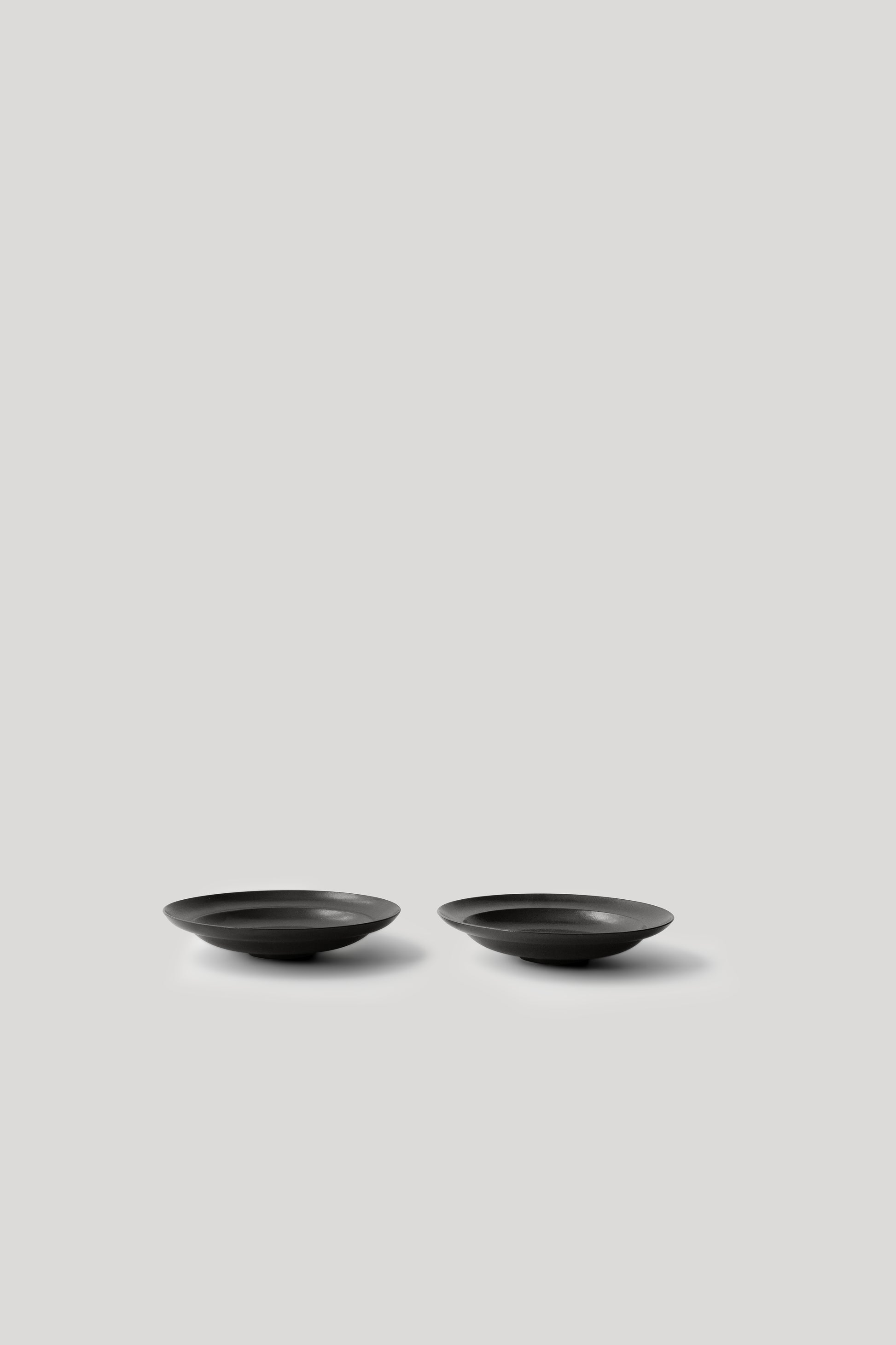 Two black ceramic bowls on a light gray background