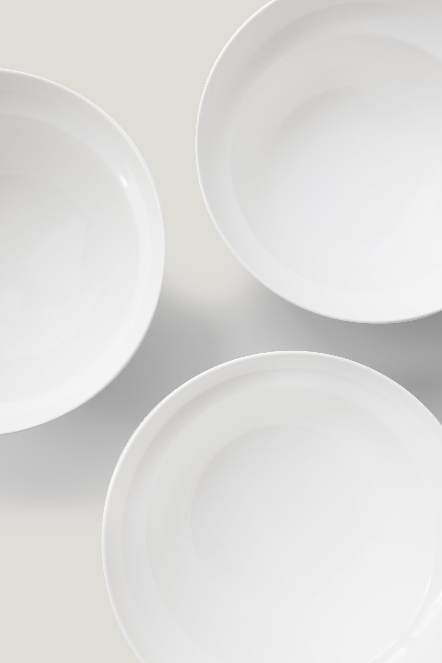 Three white ceramic plates arranged in a triangular pattern on a light gray background