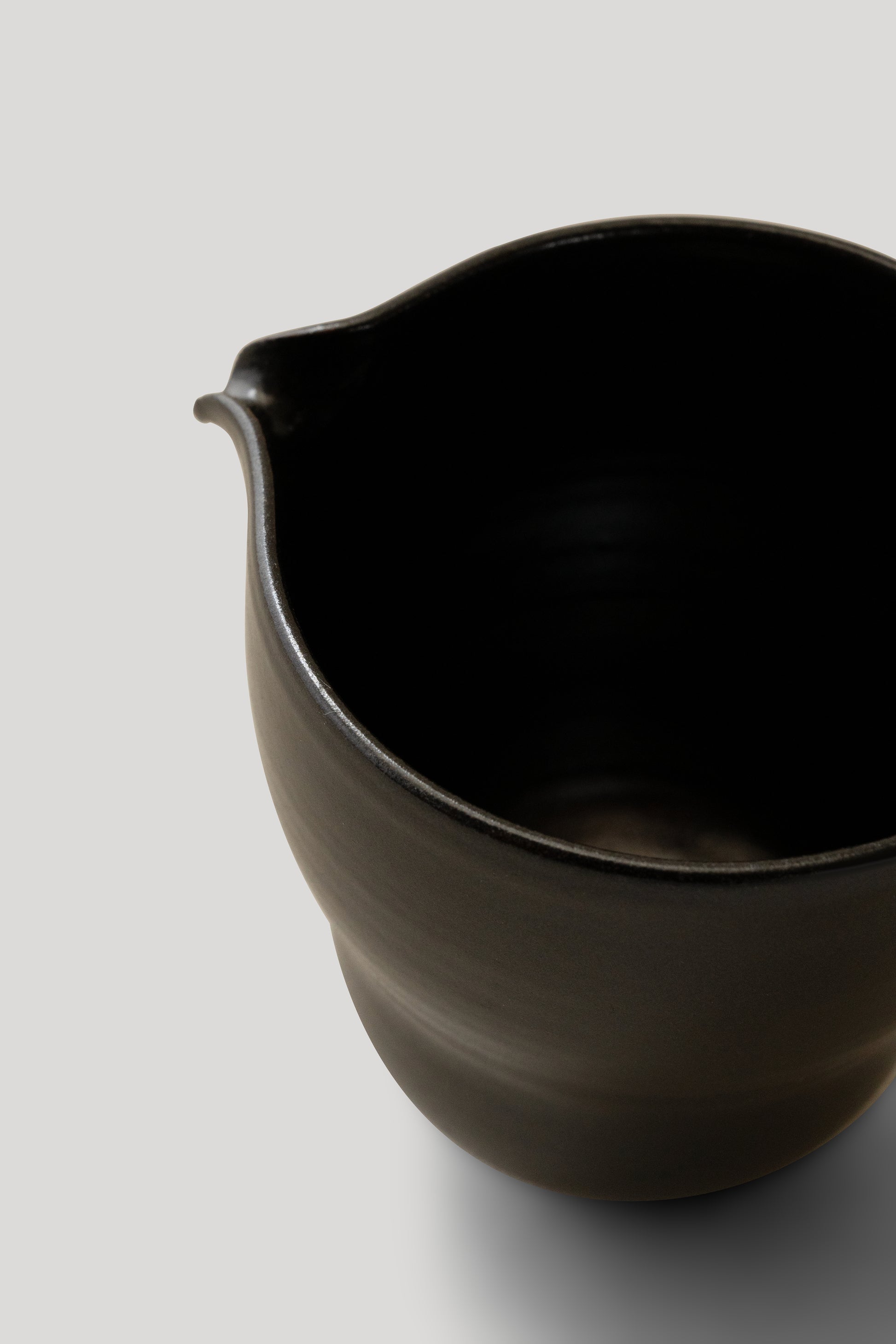 Black ceramic pitcher on a light gray background