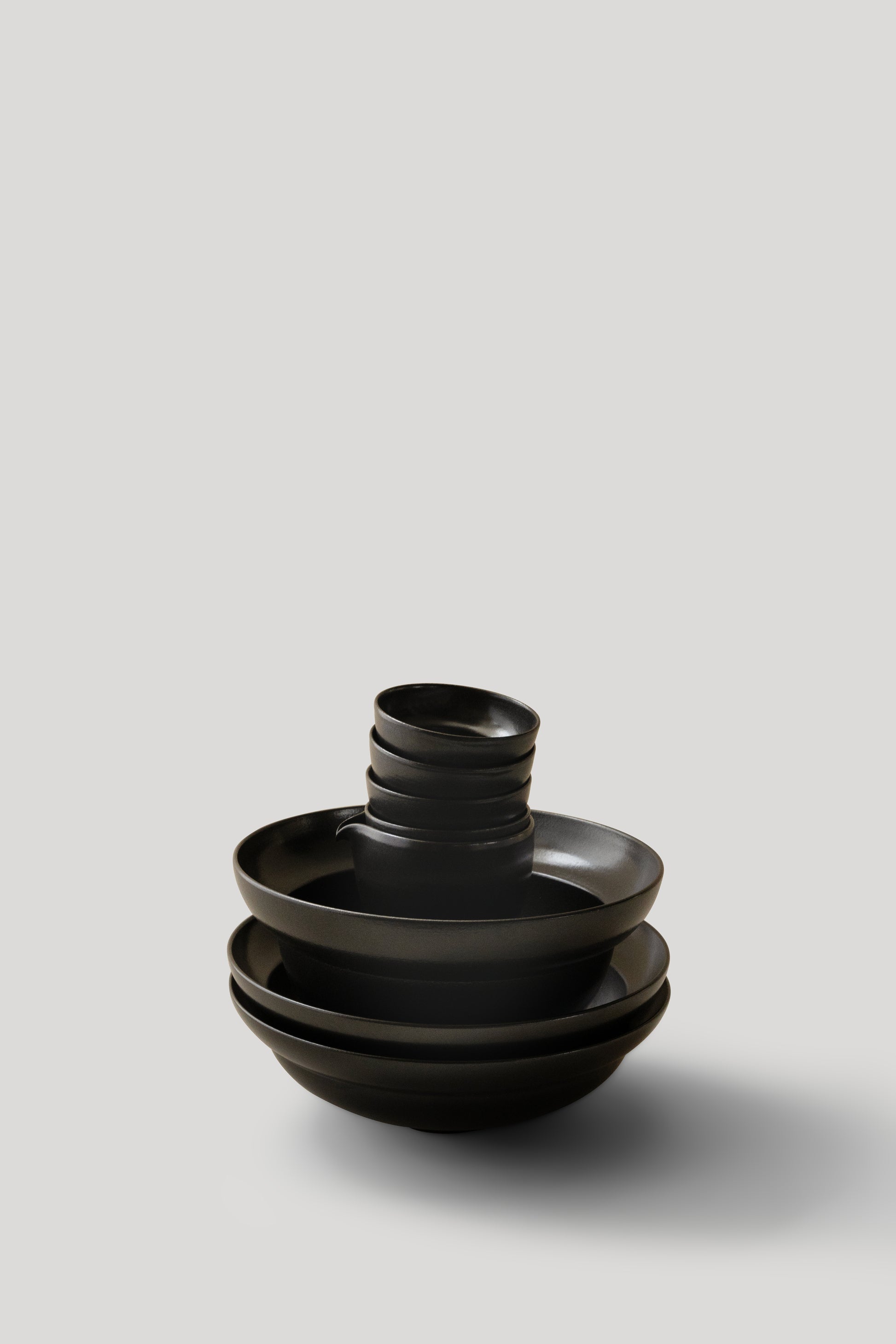 Stack of black ceramic bowls on a light gray background