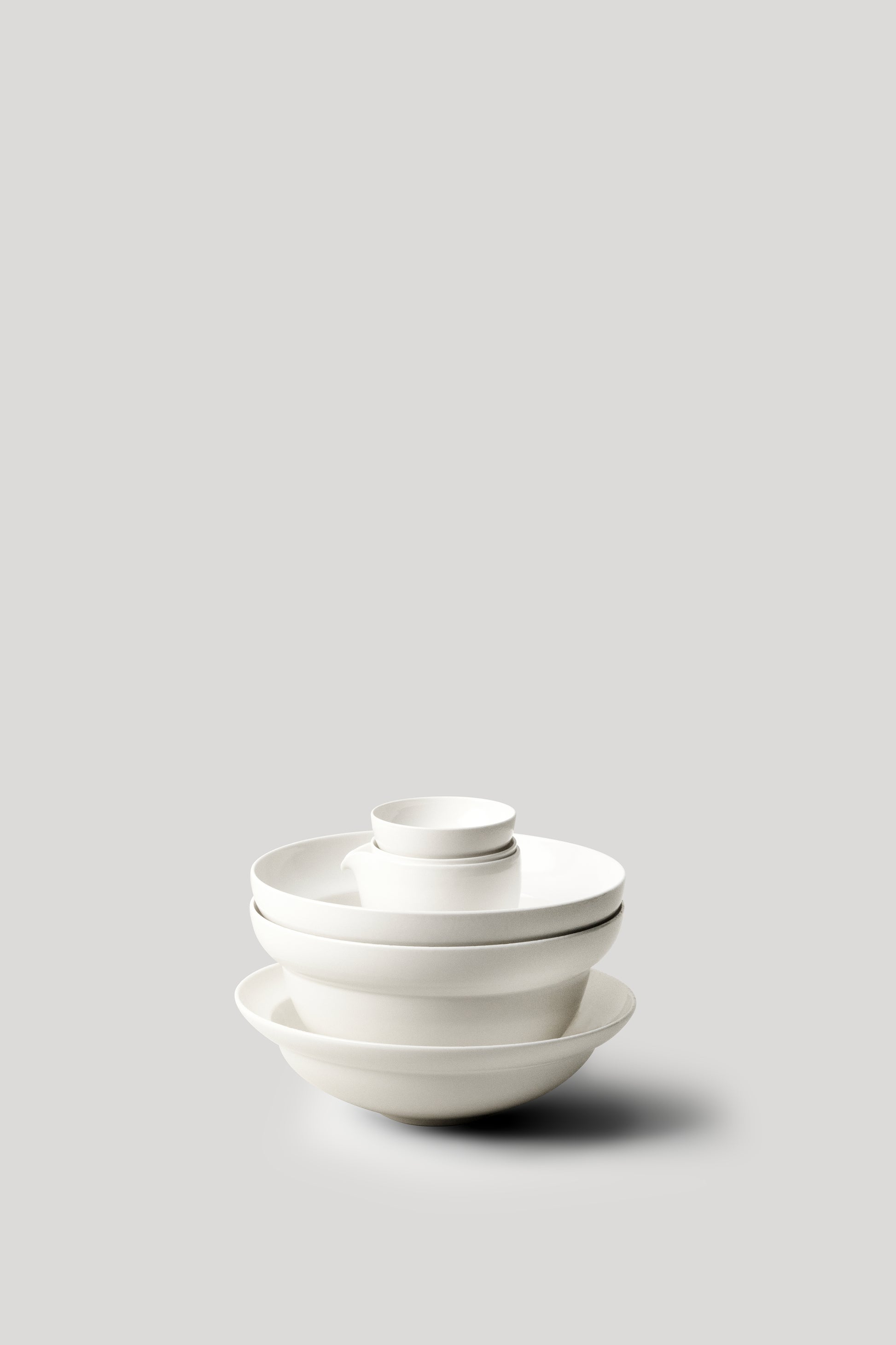 Stack of white ceramic bowls on a light gray background