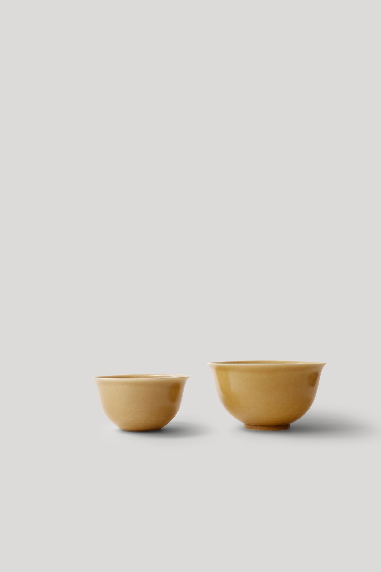 Two small mustard yellow ceramic bowls on a light gray background