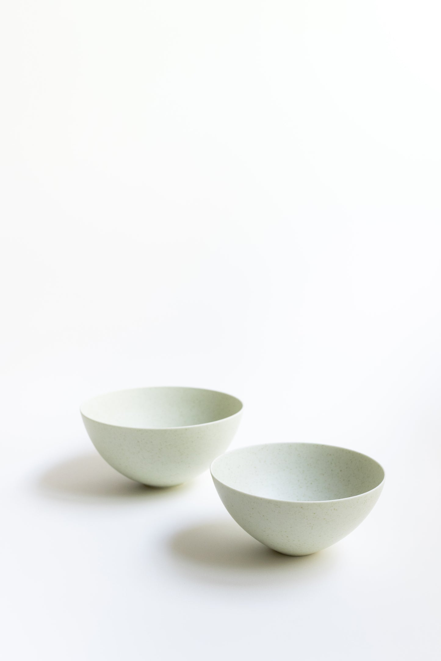 Two white ceramic bowls on a light beige background