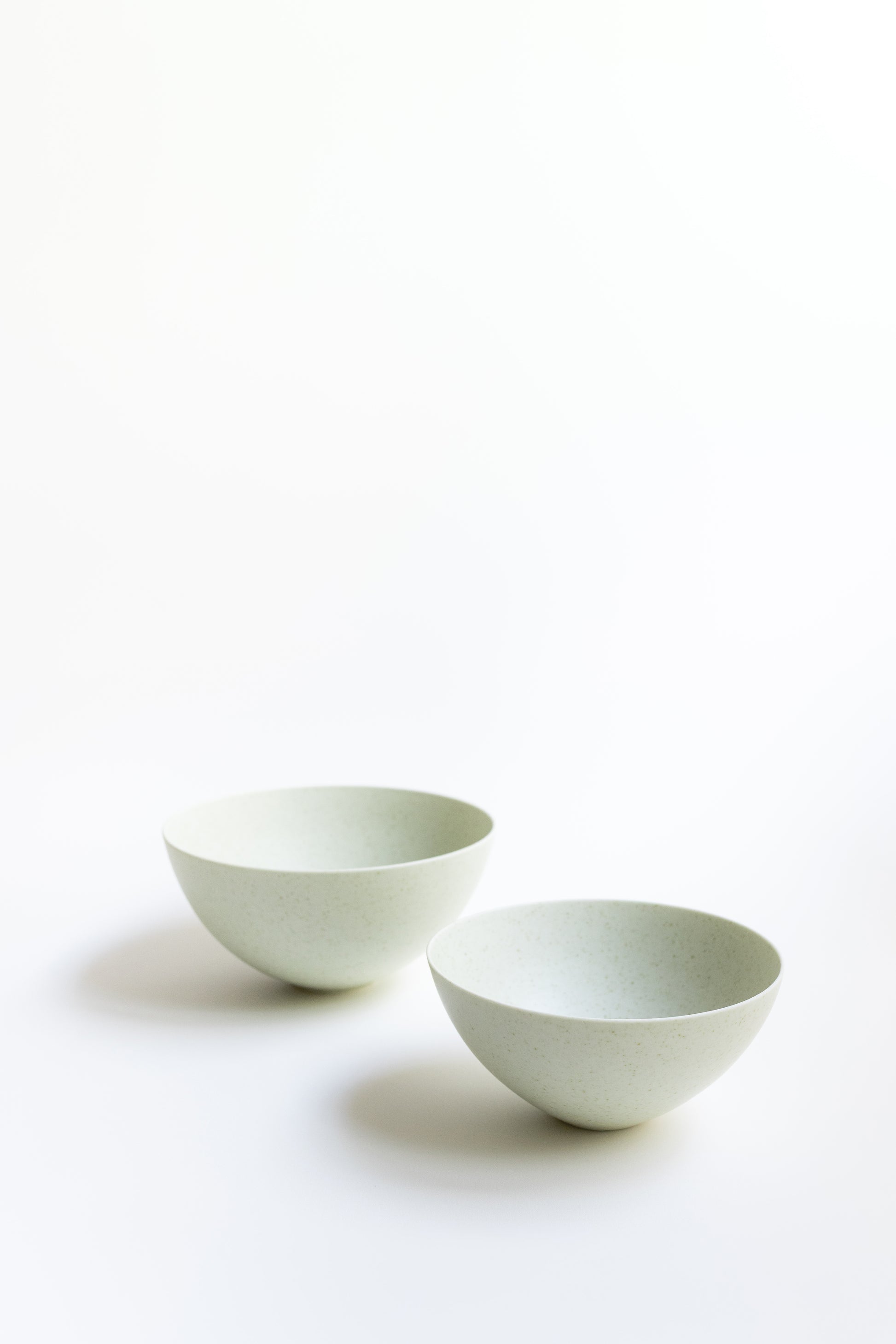 Two white ceramic bowls on a light beige background