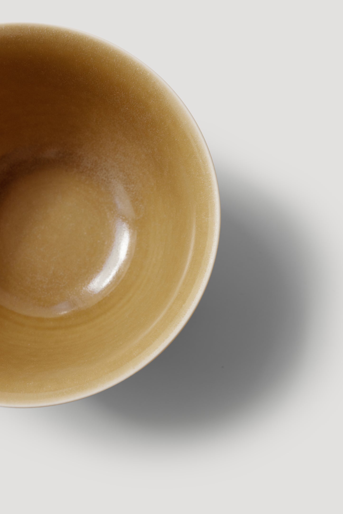 Close-up of a yellow ceramic bowl on a light gray background
