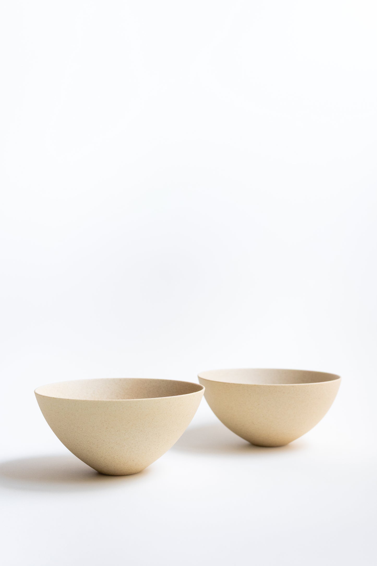 Two beige ceramic bowls on a white background