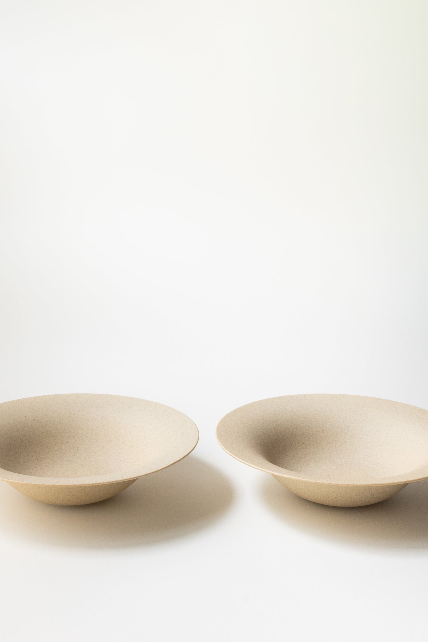 Two beige ceramic bowls on a white background