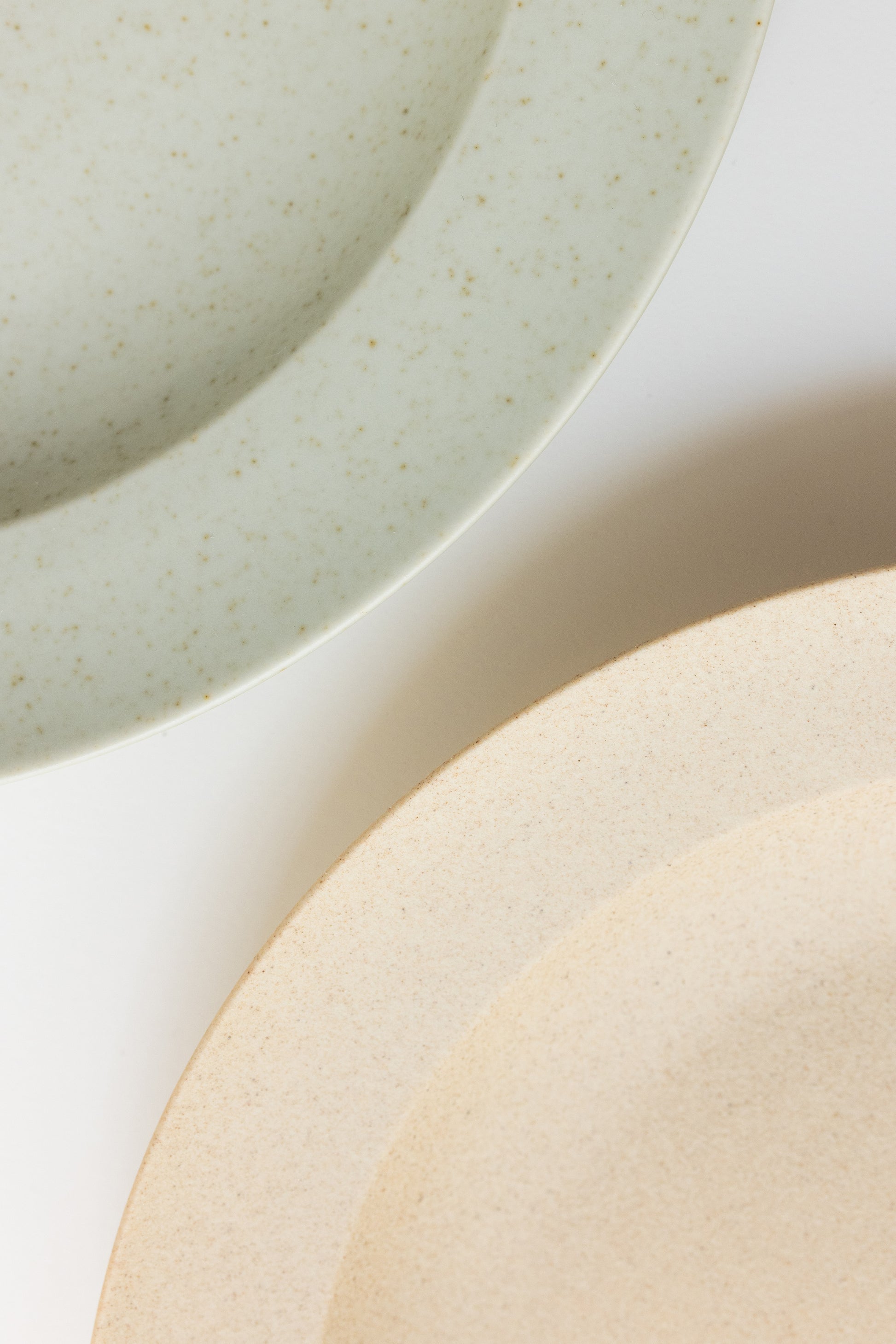 Close-up of ceramic plates with a neutral color palette on a light background