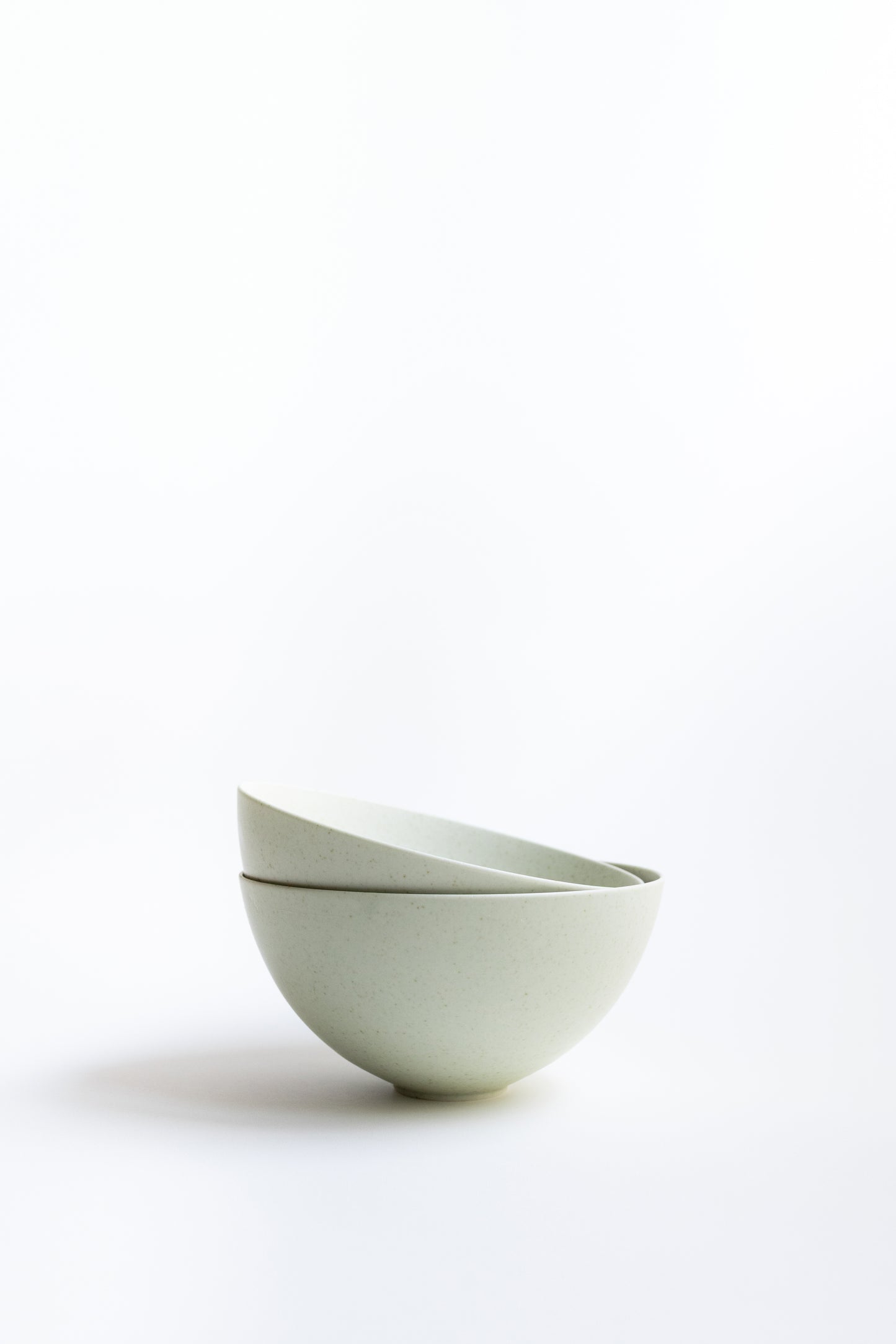 Two white ceramic bowls stacked on a white background