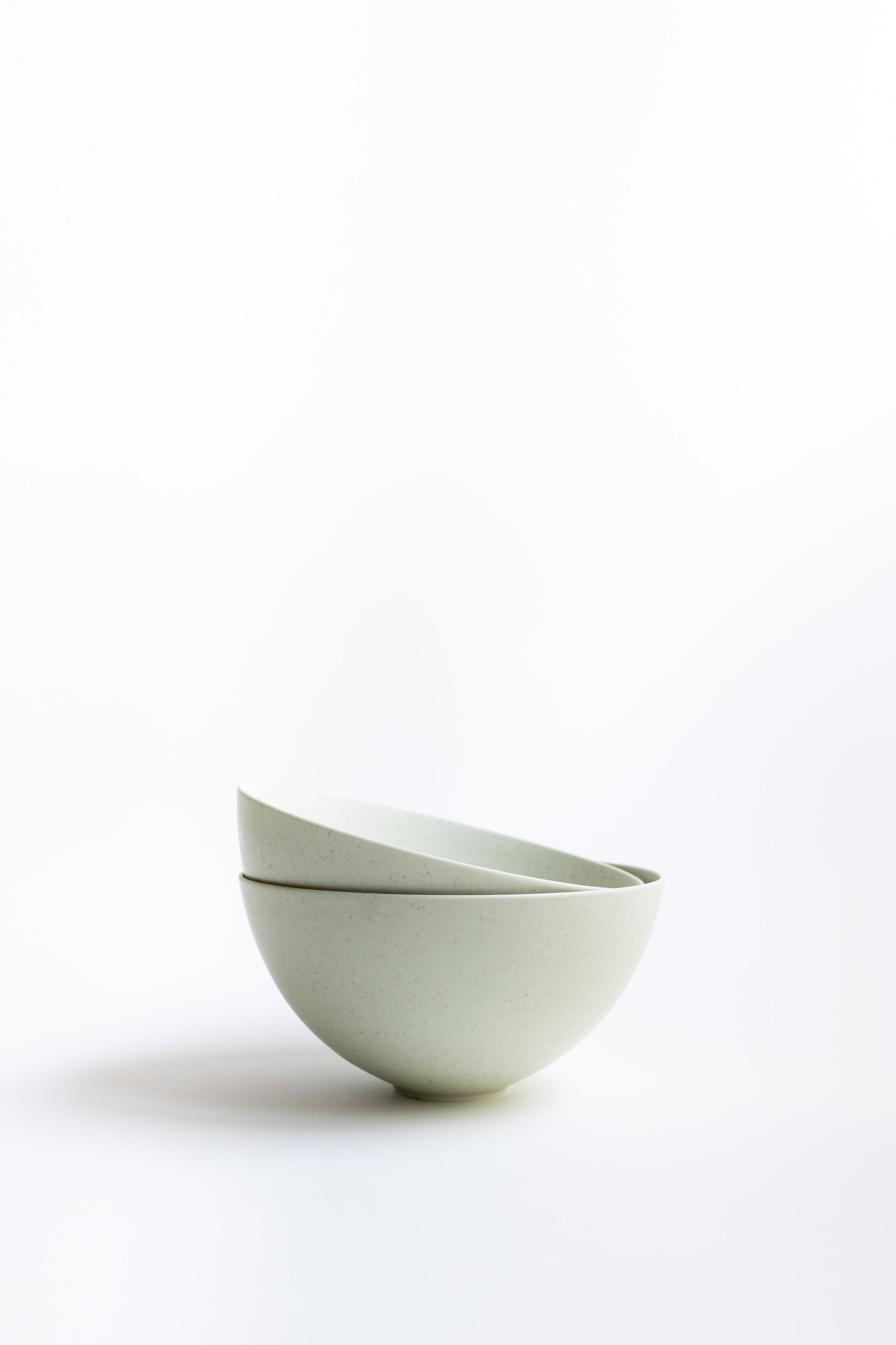 Two white ceramic bowls stacked on a white background