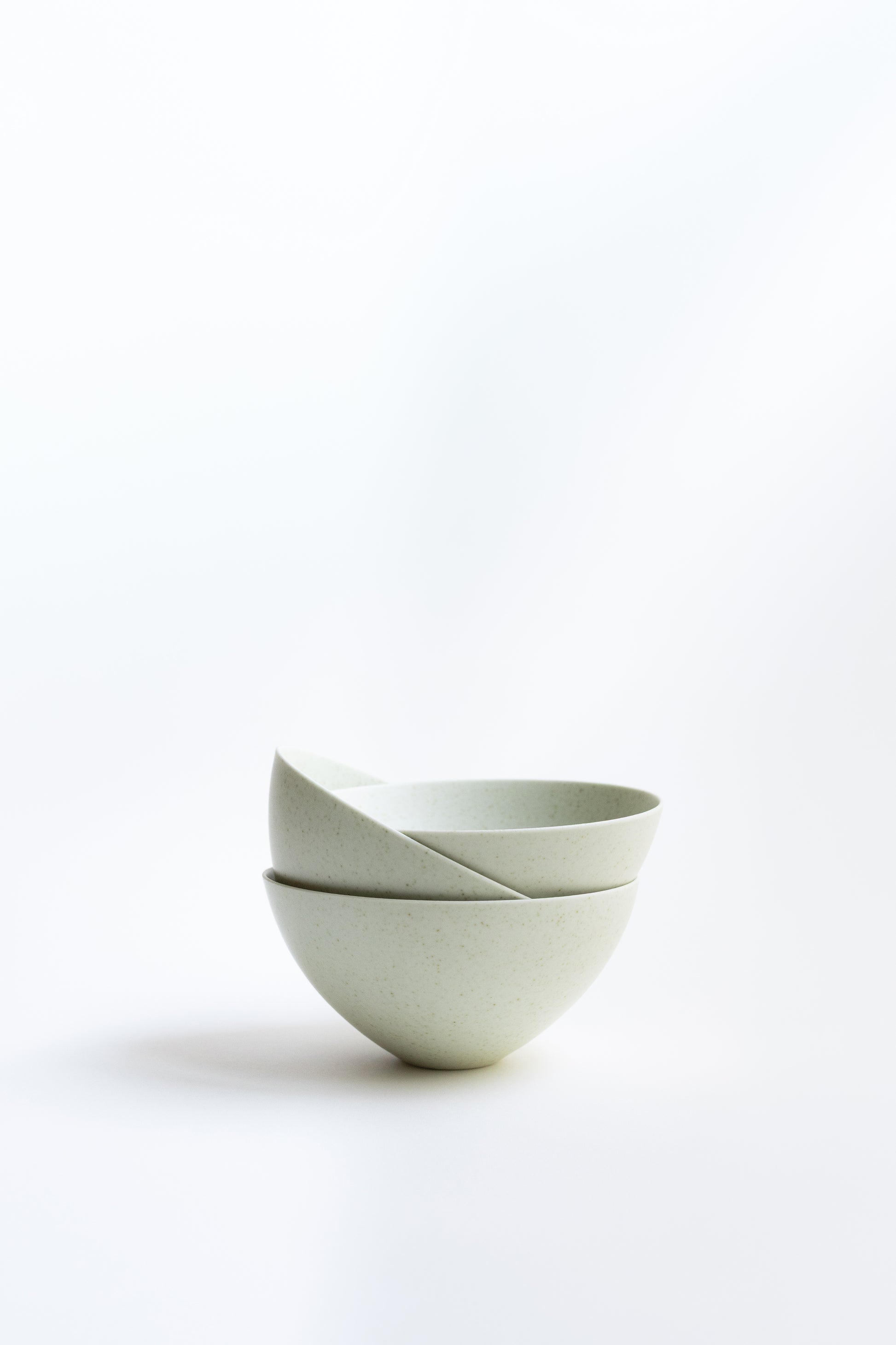 Two white ceramic bowls stacked on a light gray background