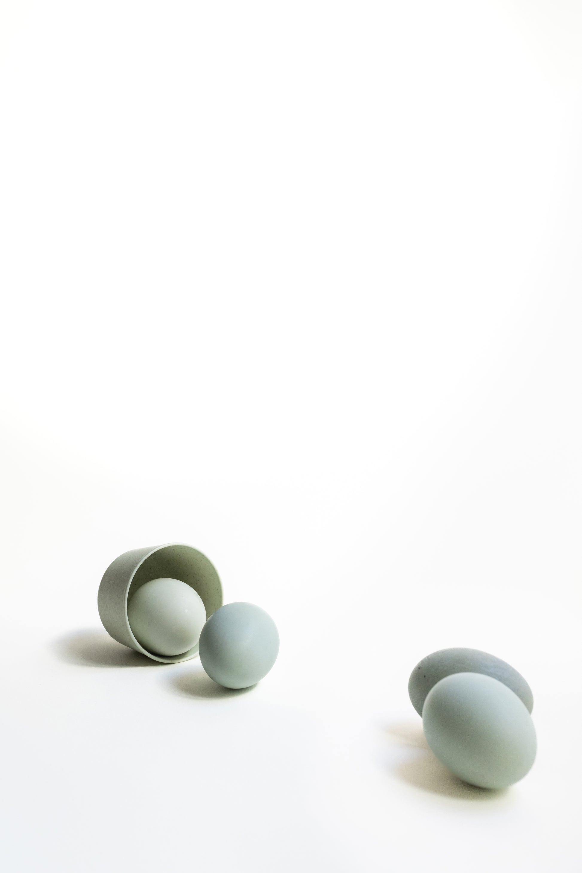 Set of light blue silicone egg-shaped containers on a white background