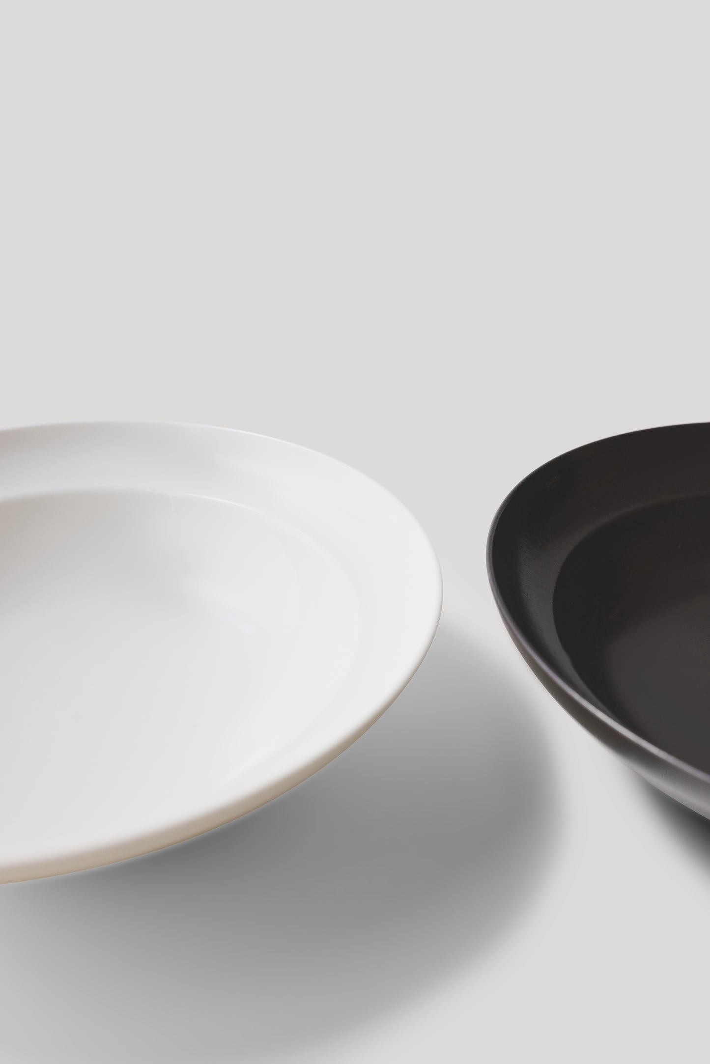 Two bowls, one white and one black, on a light gray background
