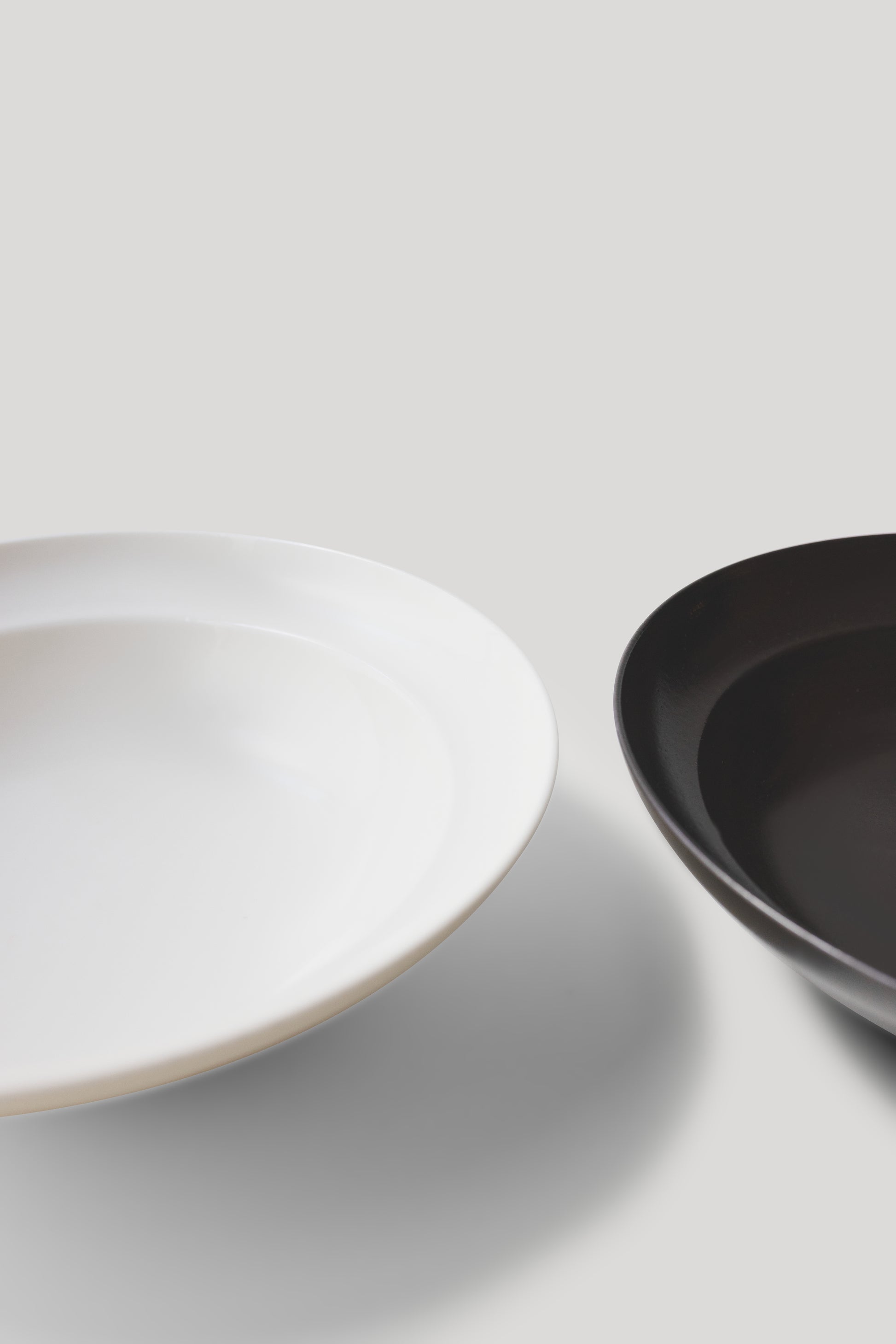 Two bowls, one white and one black, on a light gray background