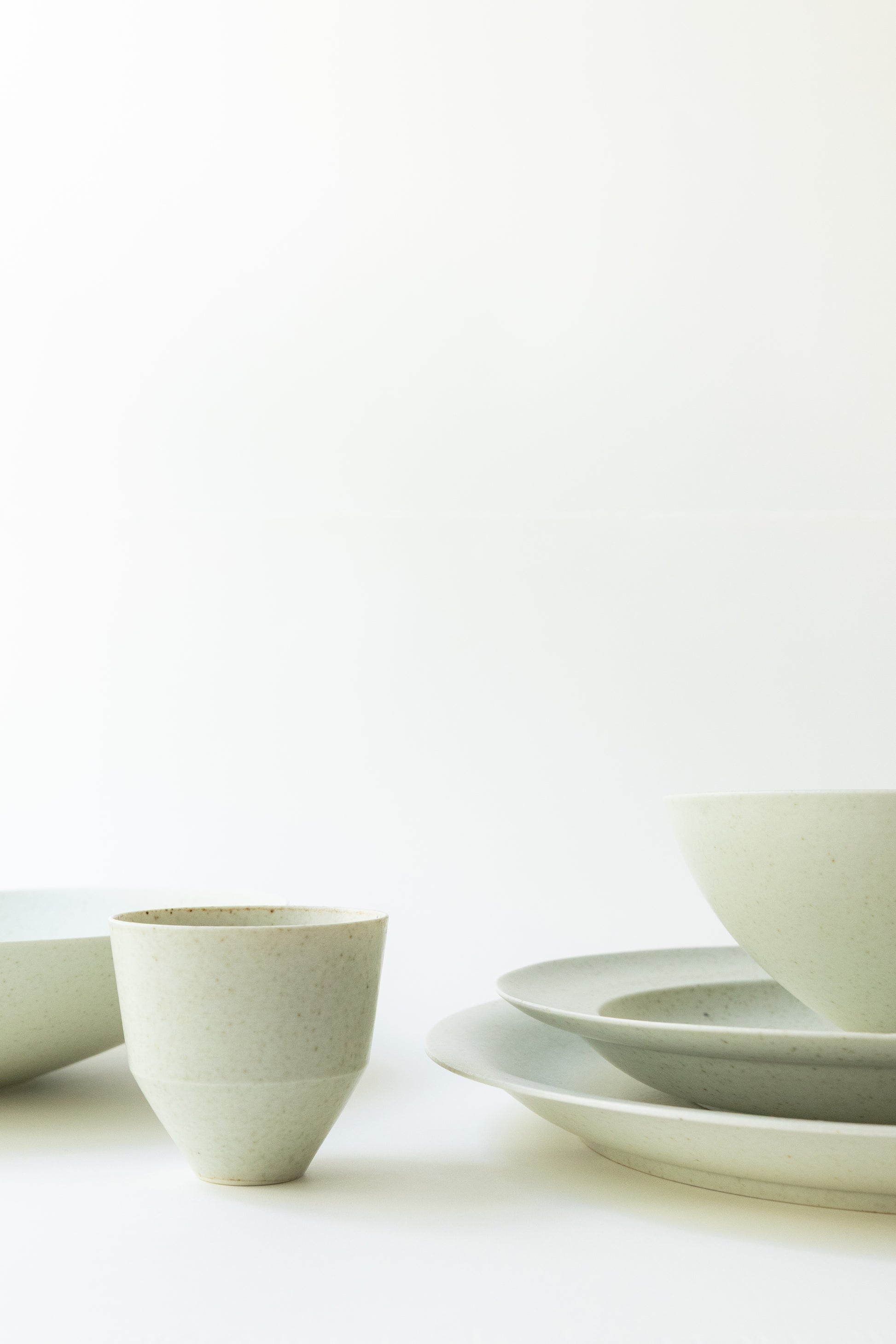Set of white ceramic bowls and plates on a light background