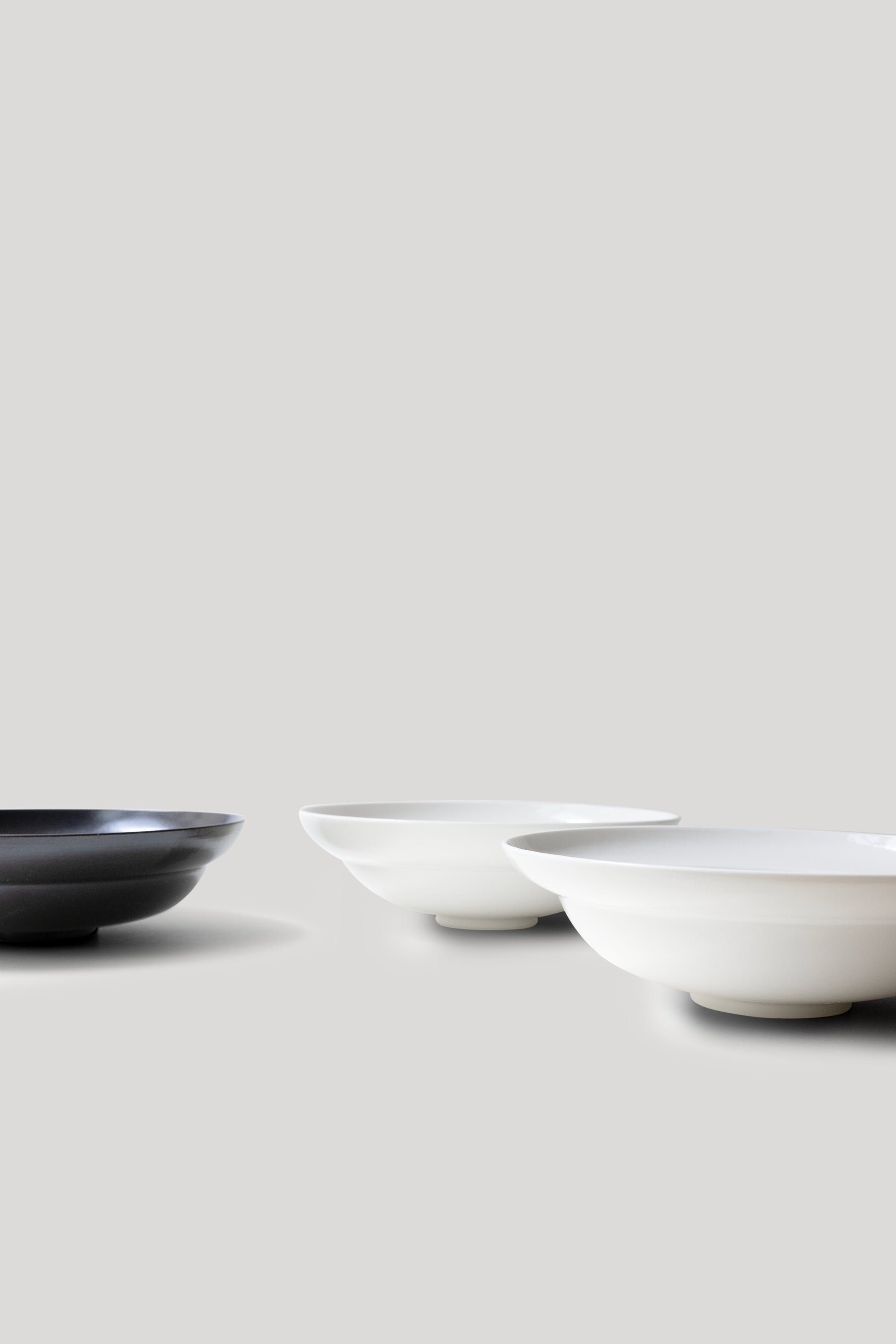 Three ceramic bowls in black, white, and gray on a light gray background